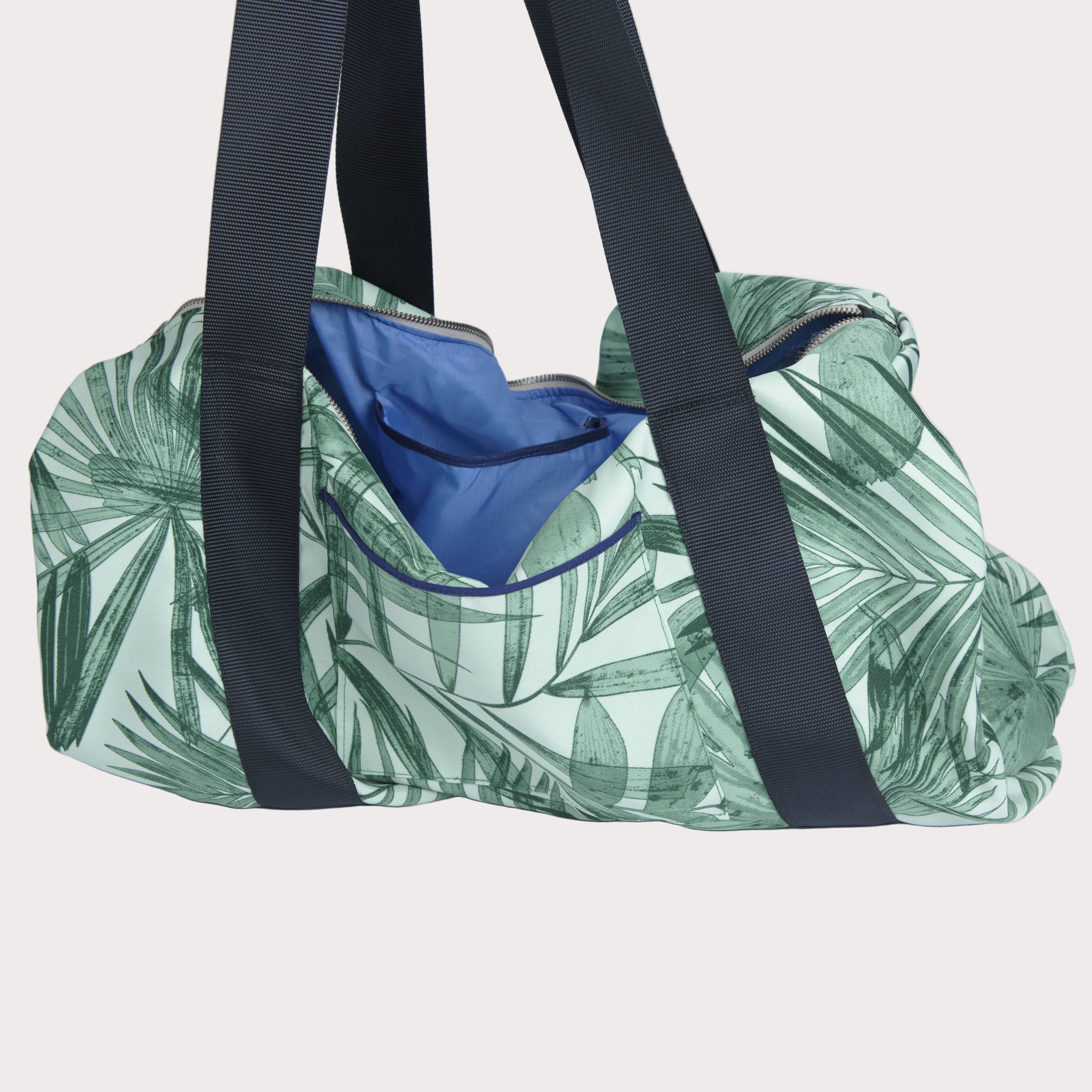 Green leaf-patterned duffel bag with black straps on a light gray background